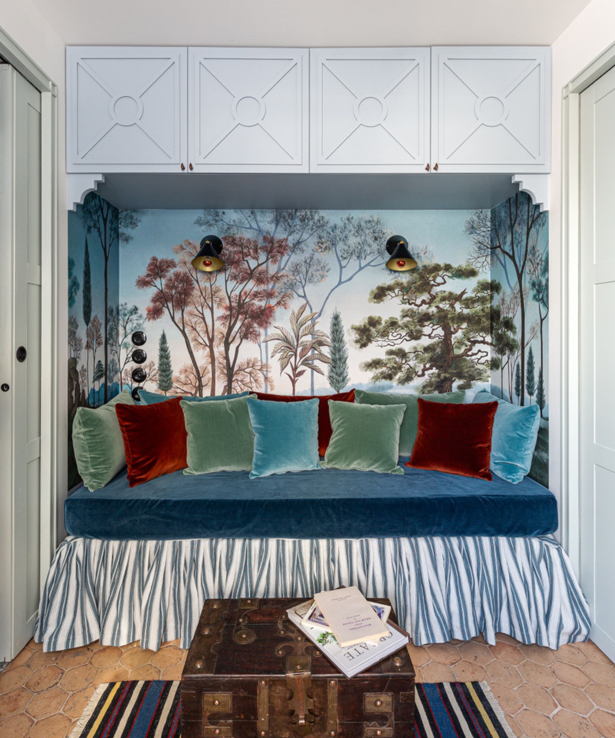 Daybed with blue cabinetry, wall mural, velvet cushions and tiled floor