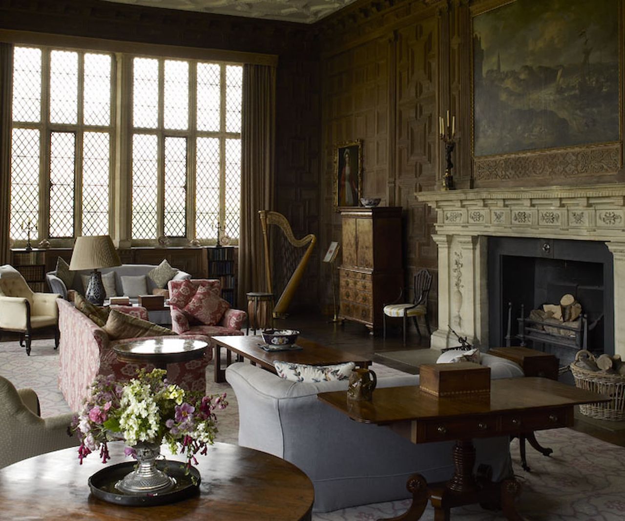 A living room with a fireplace and ancient painting on the wall