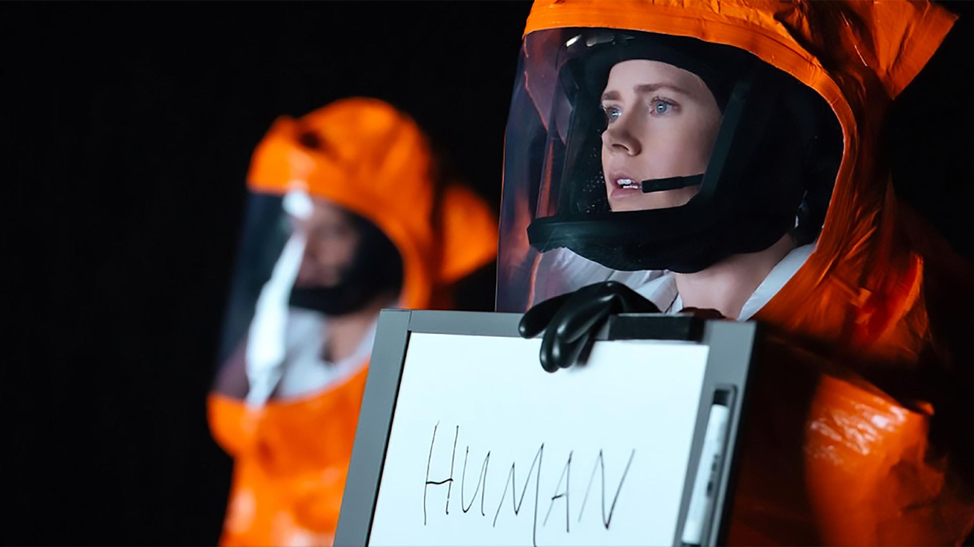 Amy Adams sostiene un cartel que dice HUMAN in Arrival