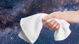 a hand holding a towel in front of a photograph of a galaxy