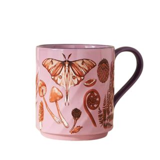A pink mug with butterfly and mushroom illustrations