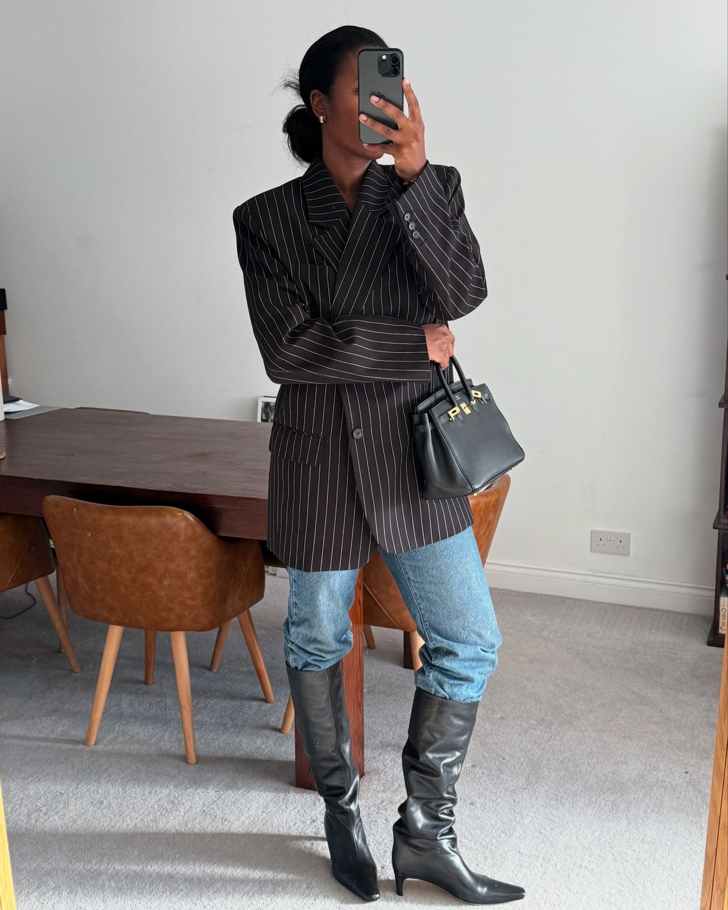 Fashion person Marylin wears the tucked knee high boot trend. She wears a pinstriped blazer, blue jeans and a black knee high boot. This image was taken from her Instagram recently.