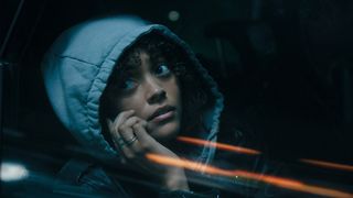 Quintessa Swindell holds up a phone to her ear while sat in a car wearing a hoodie