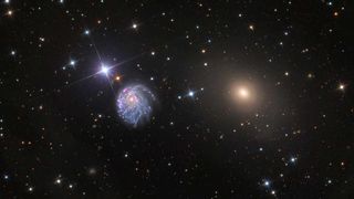 A wide-field view of the Hubble Space Telescope shows the NGC 2276 galaxy together with its smaller neighbor NGC 2300, which exerts its gravitational force on one side of NGC 2276 and causes its asymmetric shape.