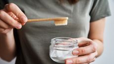 woman holding toothbrush near lid of powdery substance