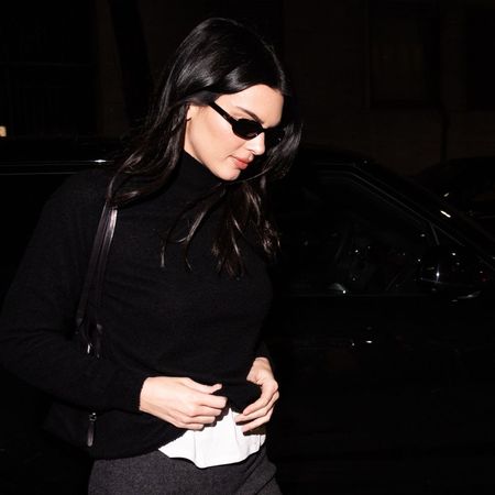 Kendall Jenner wears a grey pencil skirt with high-vamp heels and a black turtleneck.