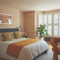 A pink bedroom painted in Little Greene's Masquerade with Masquerade Light on the ceiling and a bed with striped, ruffled bedding