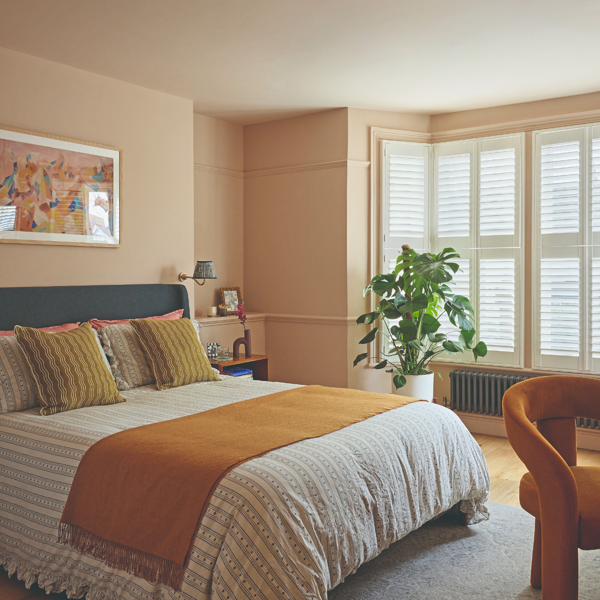 A pink bedroom painted in Little Greene's Masquerade with Masquerade Light on the ceiling and a bed with striped, ruffled bedding