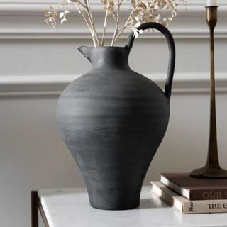 A black ceramic magnolia vase with dried flowers inside