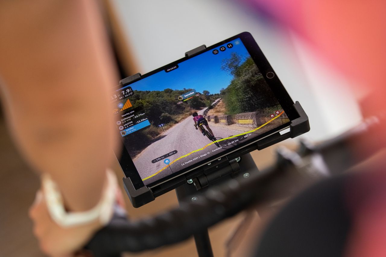 This image shows the screen of someone using the Rouvy app, with an arm and handle bars not in focus in the foreground