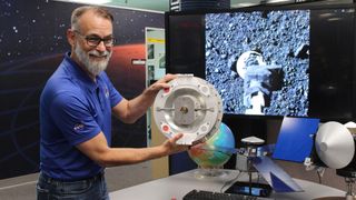 Dante Lauretta, OSIRIS-Rex principal investigator from the University of Arizona, holds replica of the Bennu sample collector device, the Touch-and-Go-Sample-Acquisition-Mechanism (TAGSAM) head that did its job.