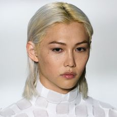 A model with bleached blonde hair and dark eyebrows.