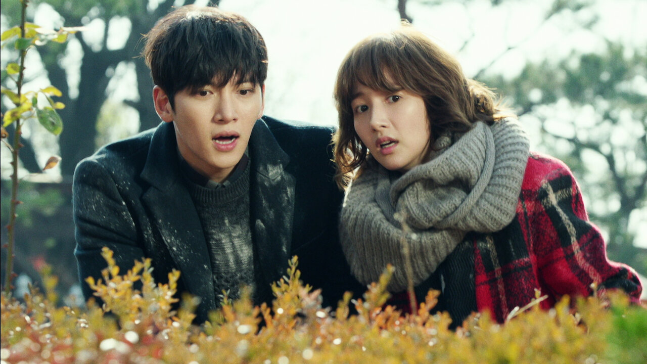 Ji Chang-wook and Park Min-young wearing coats laying on the ground with frosted grass in the k-drama 'Healer'.