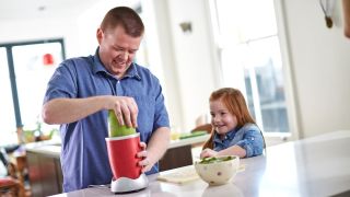 Man making healthy smoothie with daughter