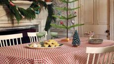 Red and white leaf tablecloth with green frosted coupe glasses and a Christmas tree candle