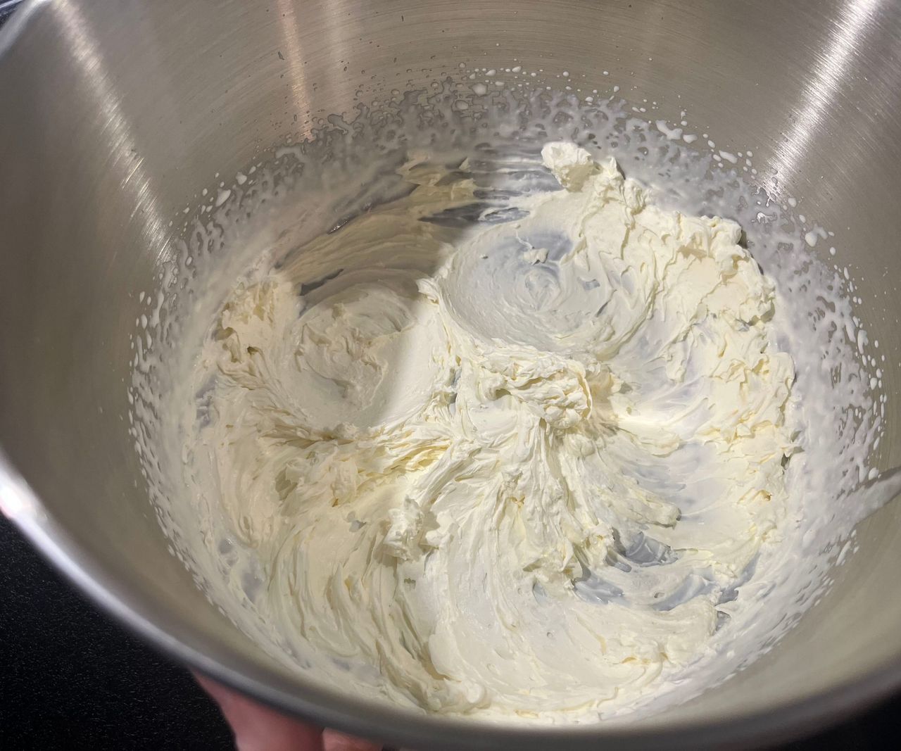 A close up of freshly whipped cream in a stand mixer bowl
