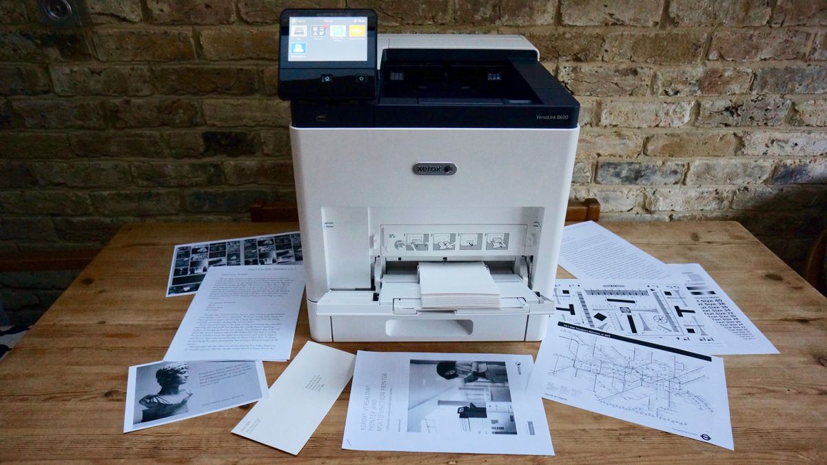 The Xerox VersaLink B600DN in a home office on a desk against a brick wall during our tests
