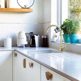 white kitchen with white worktops and kitchen sink with gold tap