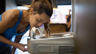 A gym goer drinks from a water fountain