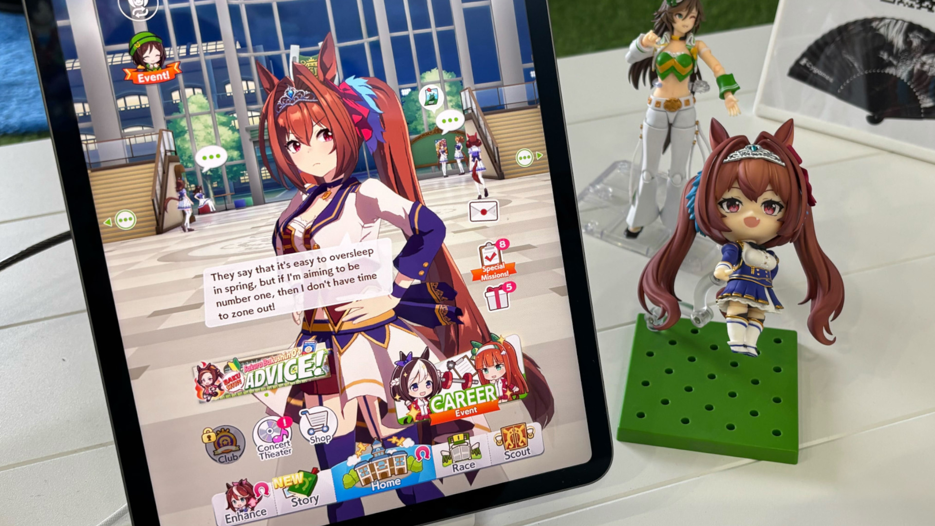 A photo from the 2025 Kentucky Derby's Umamusume: Pretty Derby booth showing the game in action on a big tablet, with nearby figures of characters from the game