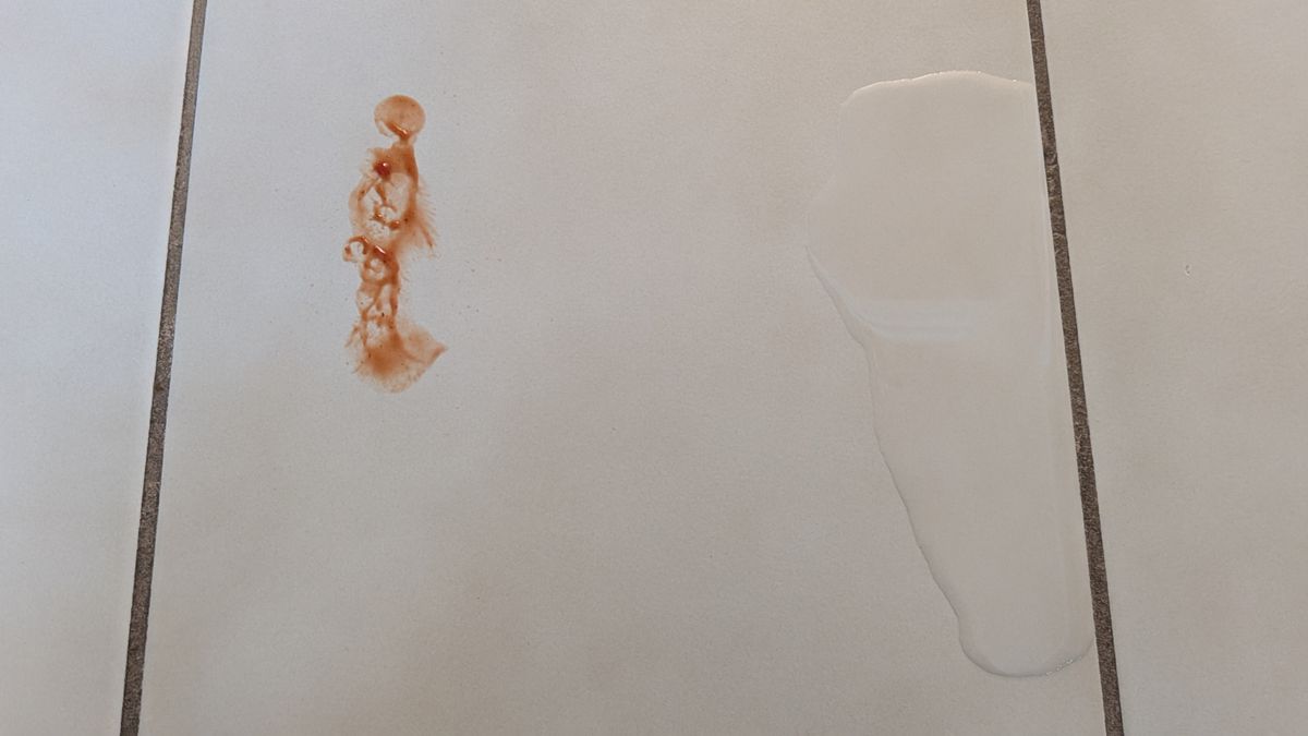 Ketchup smear and water spillage on tiled floor before the mopping test