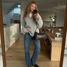 a woman wears jeans and a sweater