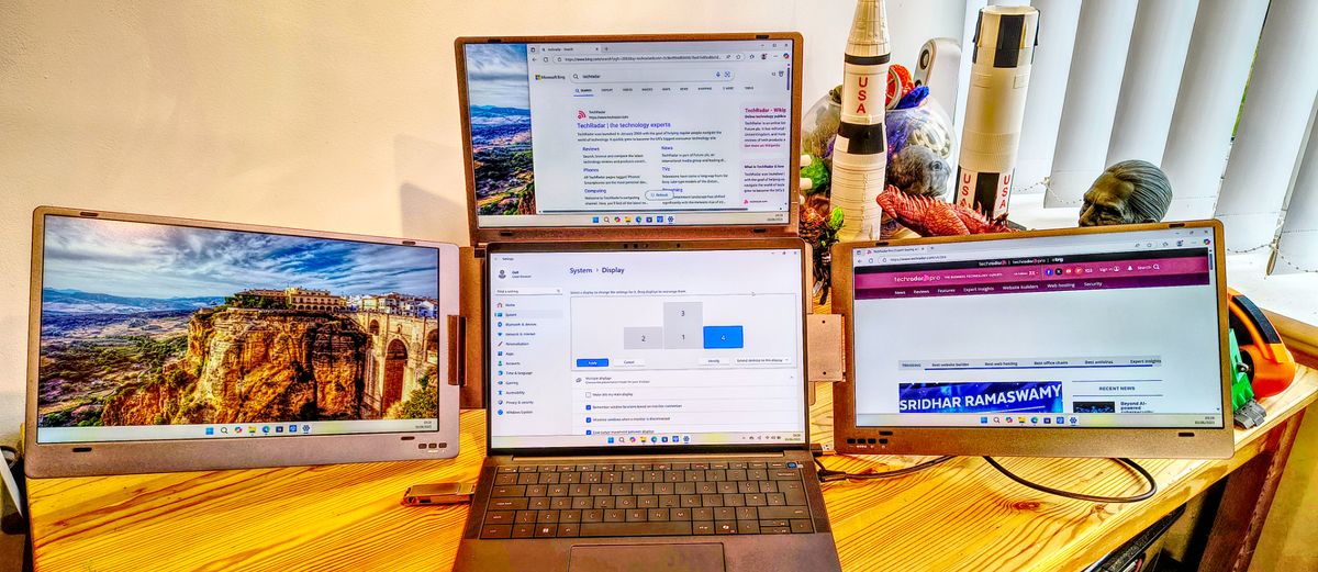 Triple screen laptop extender in professional work environment showing real-world business productivity applications