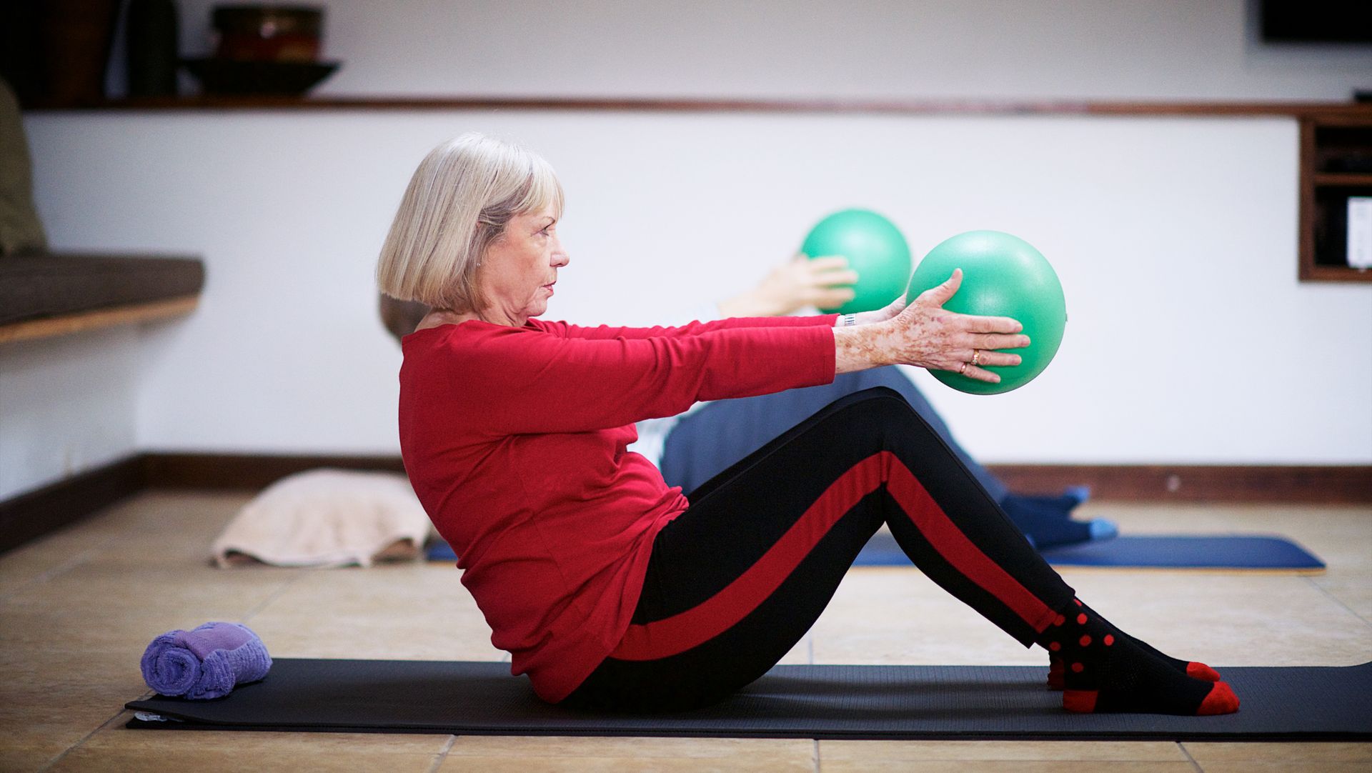 Image of a woman‌ doing seated​ ball squeeze exercise