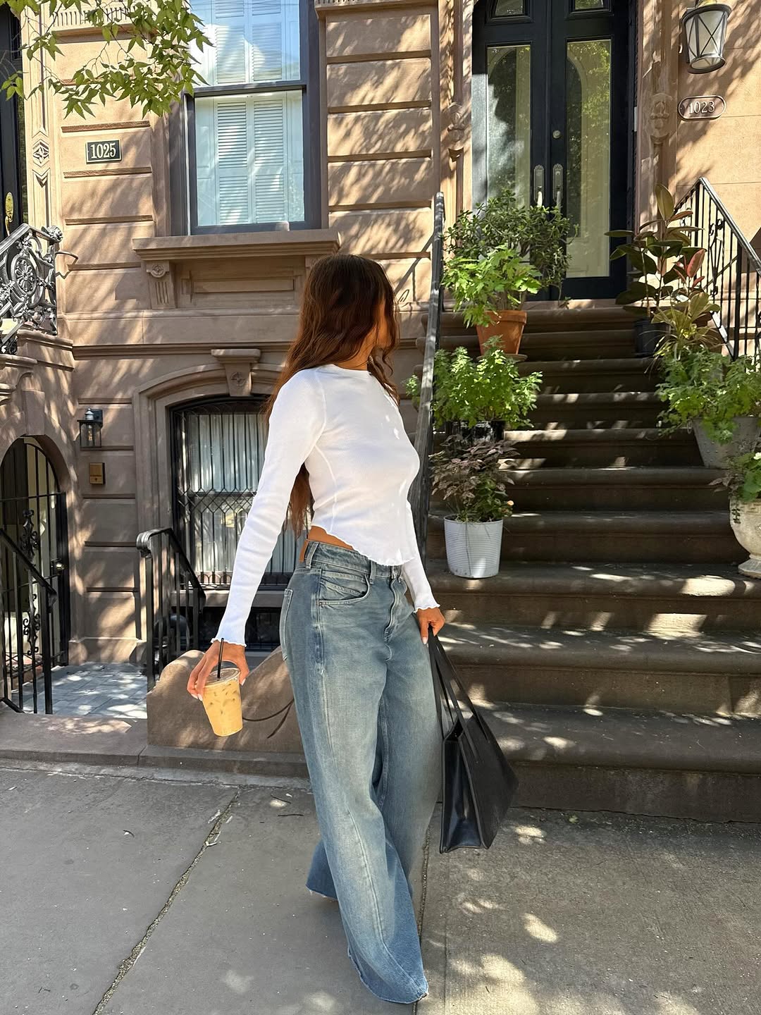 Woman wearing long, baggy jeans fall denim trend 2025.