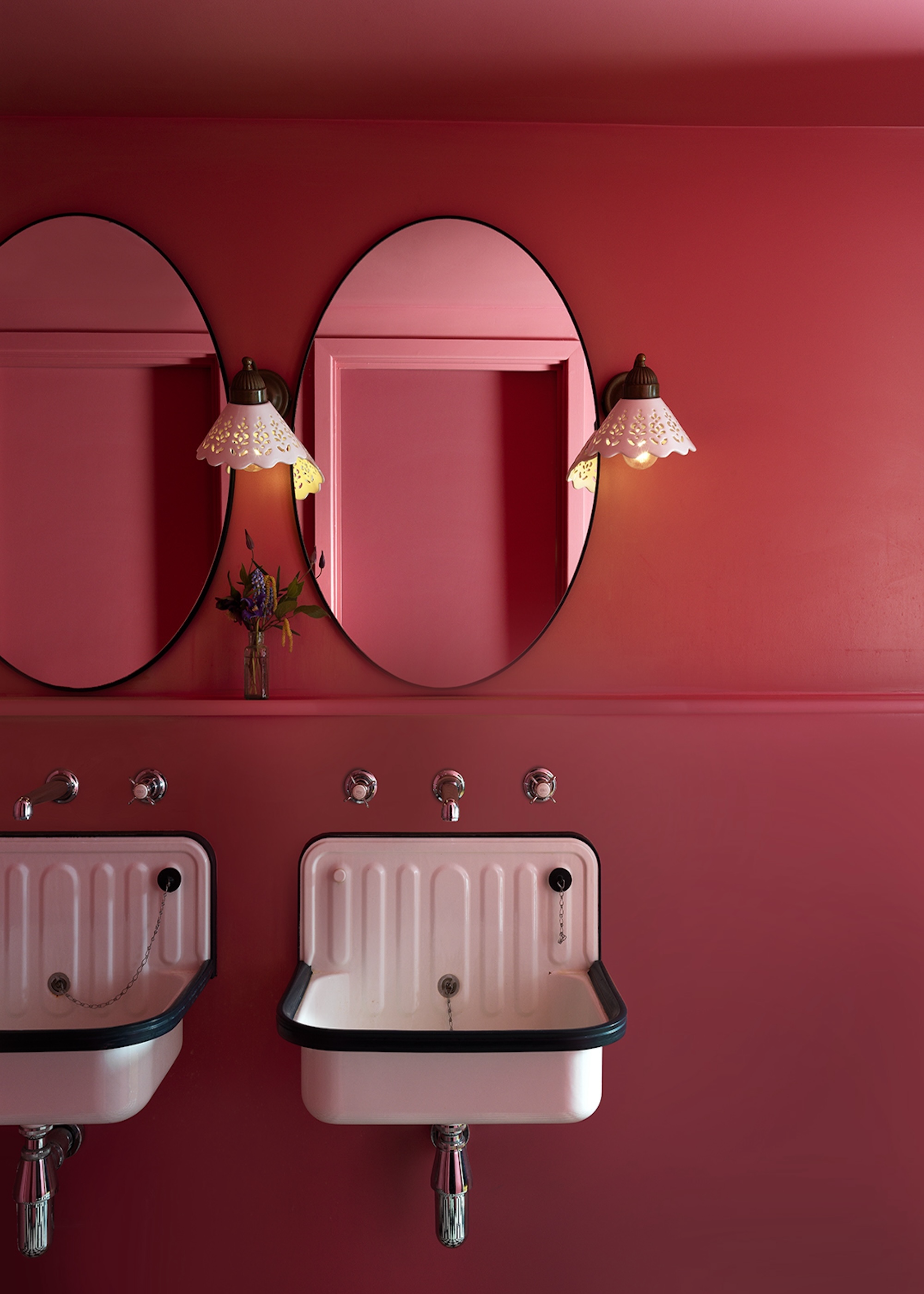 A red painted bathroom with double mirrors and double sinks