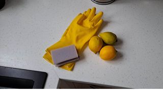 Yellow gloves, sponge and three lemons