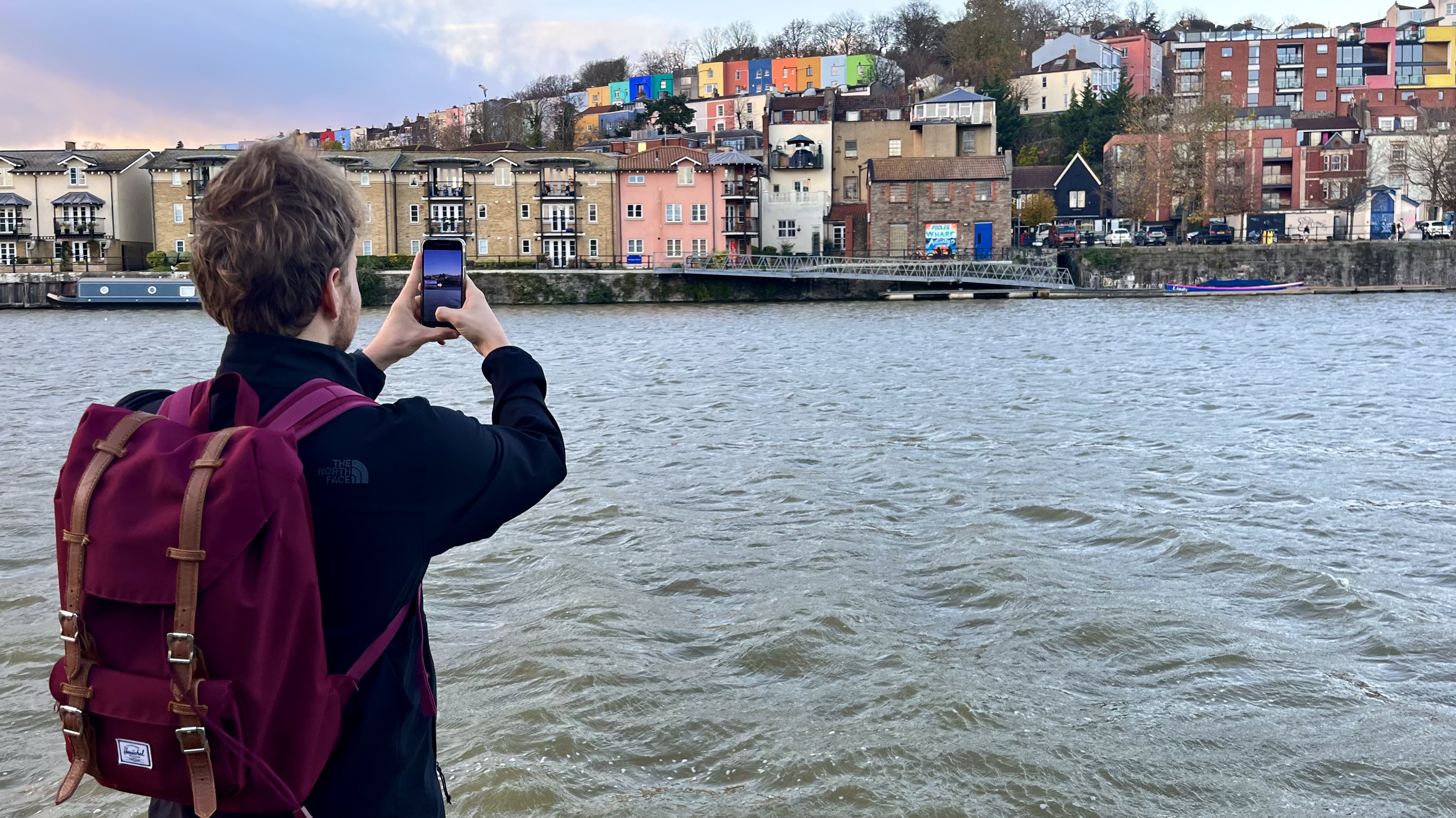 Person photographing waterfront with iPhone 13