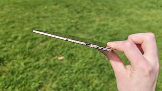 The Honor Magic V6 being held in a sunny field. 