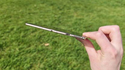 The Honor Magic V6 being held in a sunny field. 