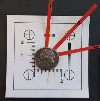 This coin, called a denarius, was minted by Rome 108 B.C.-107 B.C and likely made of silver that originated in southeastern Spain. The three red marks indicate where the coin was drilled into for purposes of accessing unweathered metal. 