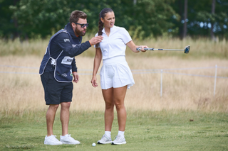 Female golfer getting tips from her caddie on the putting green