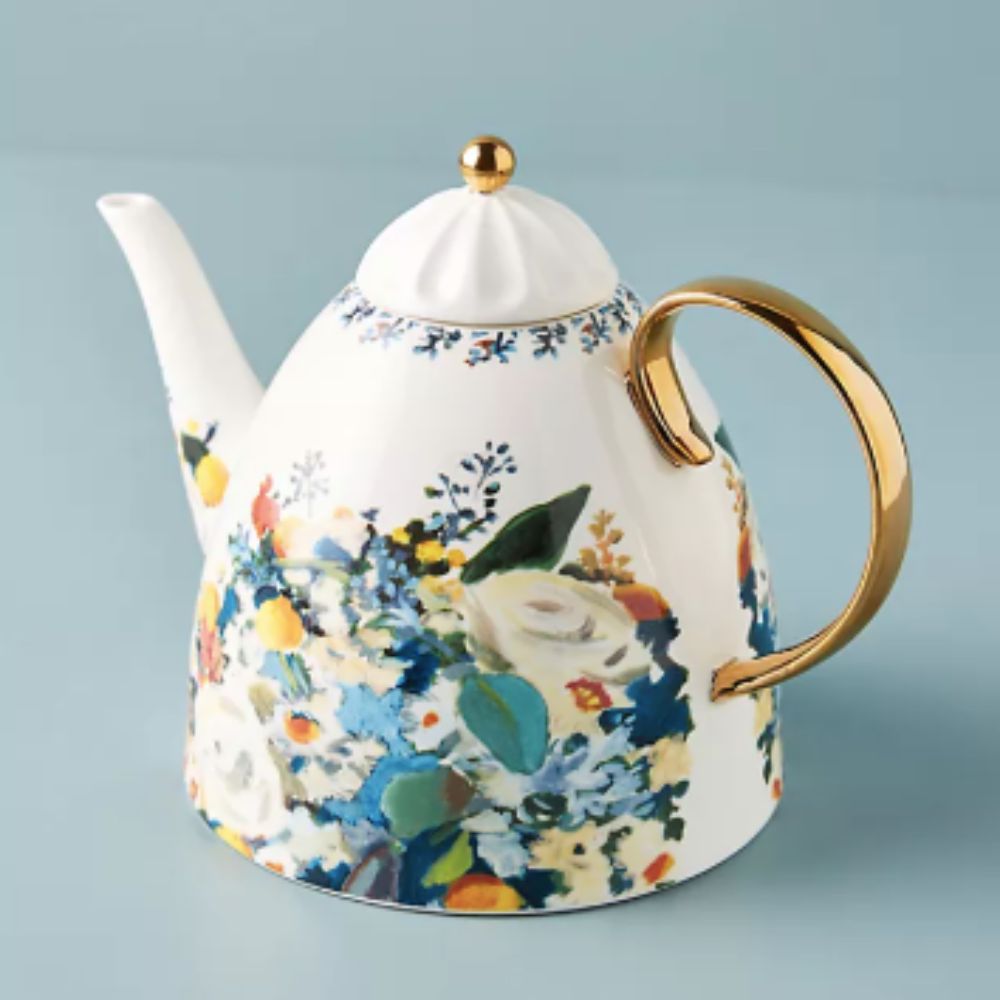 floral vintage style teapot with a gold handle on plain background