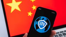 Hand with mobile phone and VPN application, Chinese flag on laptop screen on the background