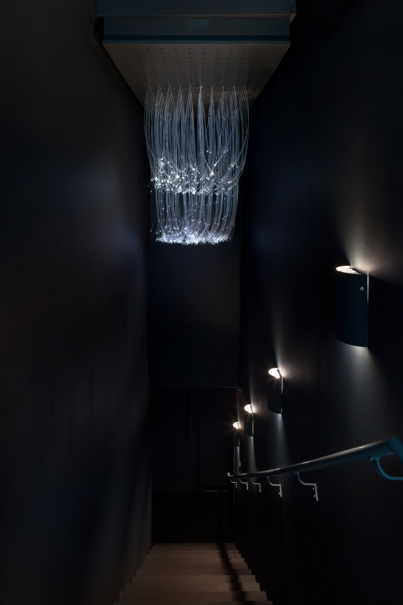 A jelly fish-like blue lamp and a dark staircase