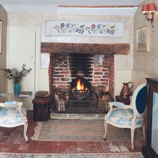 tudor inglenook brick fireplace with decorative panel and regency style chairs