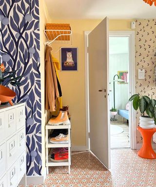 A colorful small entryway with shoes, coats, and a white storage unit