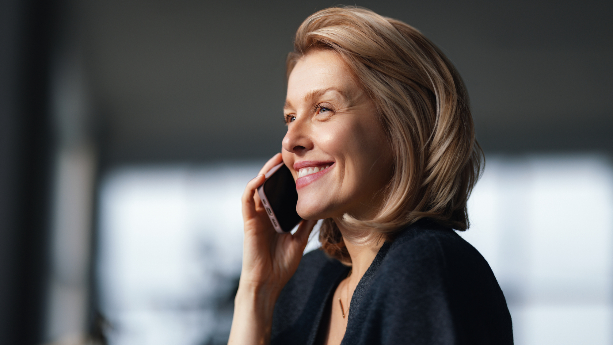 A person, smiling while speaking on their phone.