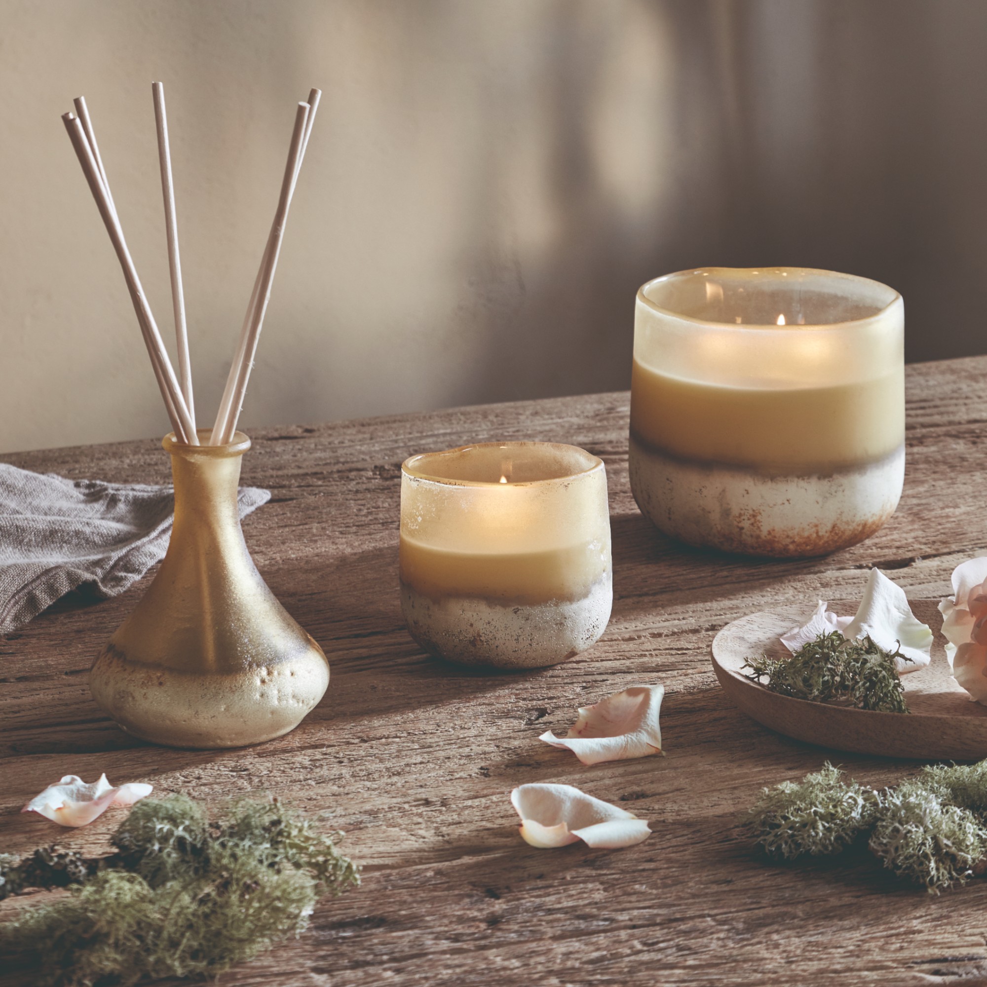 The Oakmoss &amp;amp; Rose Home Fragrance Collection from Nkuku on a rustic wooden table