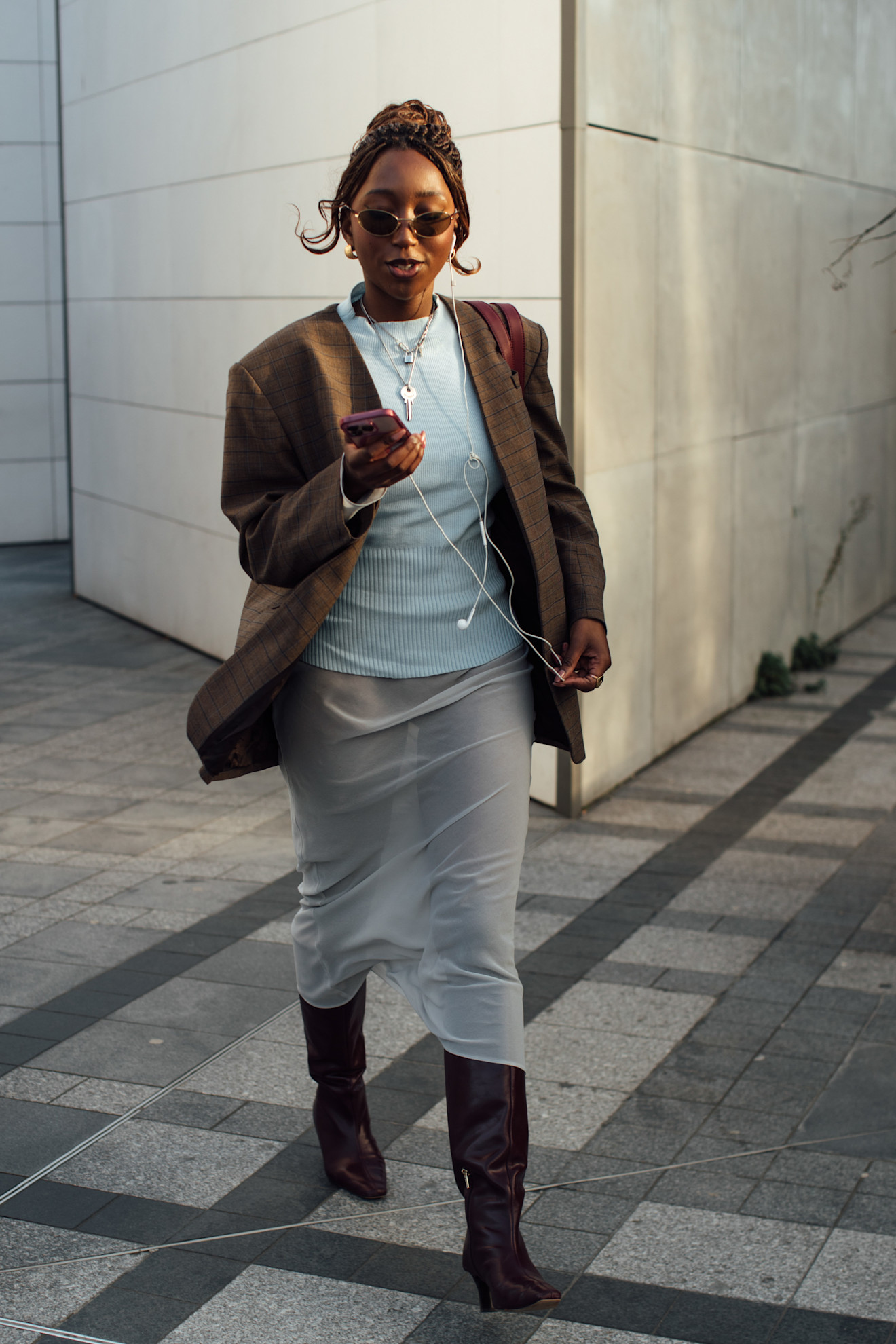 a woman in a brown jacket and white skirt with boots and a brown ponytail