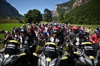 The pack of riders is temporarily immobilized by race regulators front due to protest action on the race route during the 10th stage of the 109th edition of the Tour de France cycling race 1481 km between Morzine and Megeve in the French Alps on July 12 2022 Photo by Marco BERTORELLO AFP Photo by MARCO BERTORELLOAFP via Getty Images