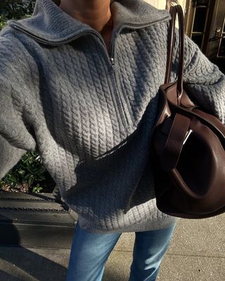 Woman wearing a gray sweater and jeans.