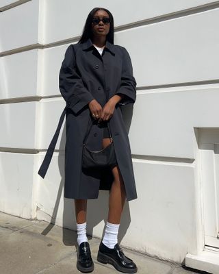 Woman wearing a black and white outfit with a trench coat.