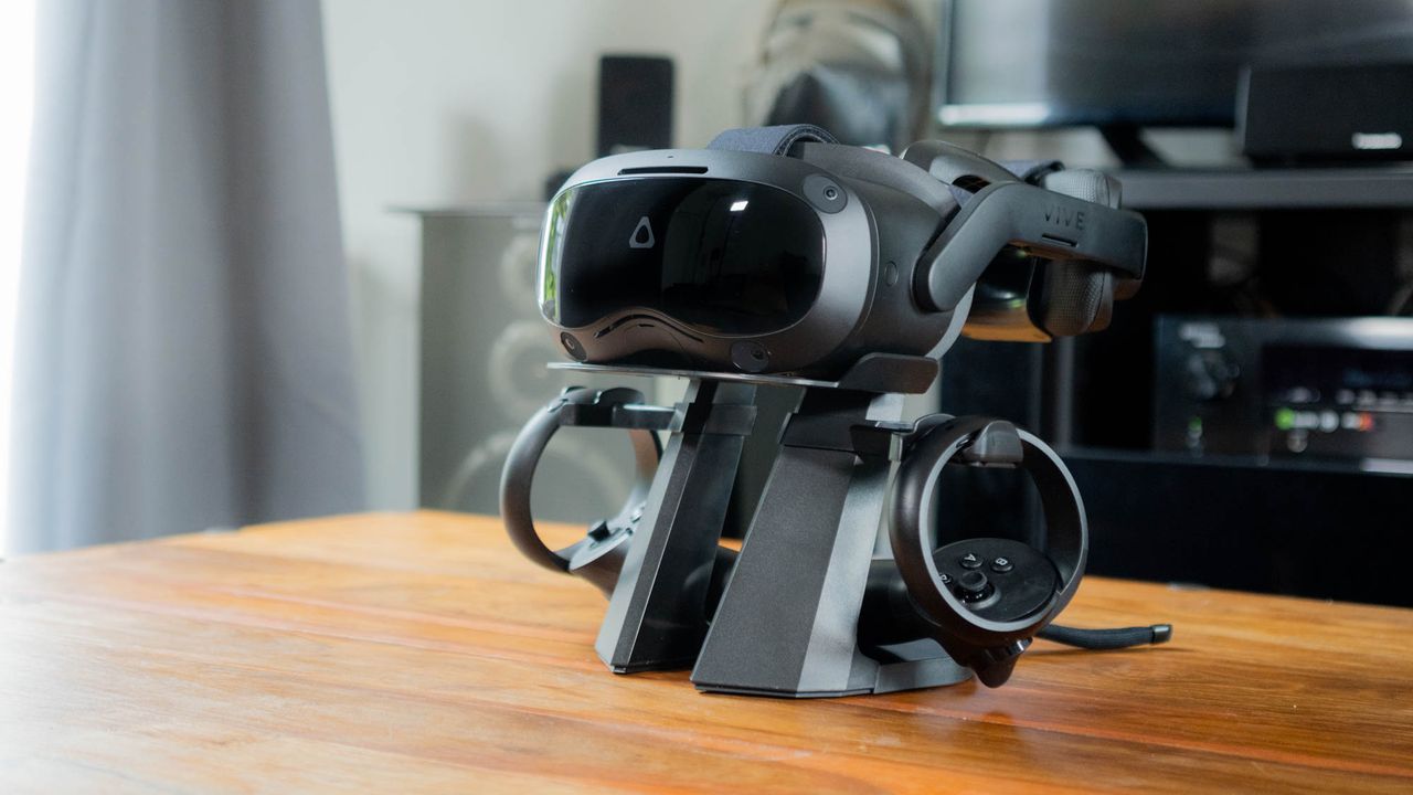 A photograph of the HTC Vive Focus 3 and its controllers, mounted on a stand on a coffee table
