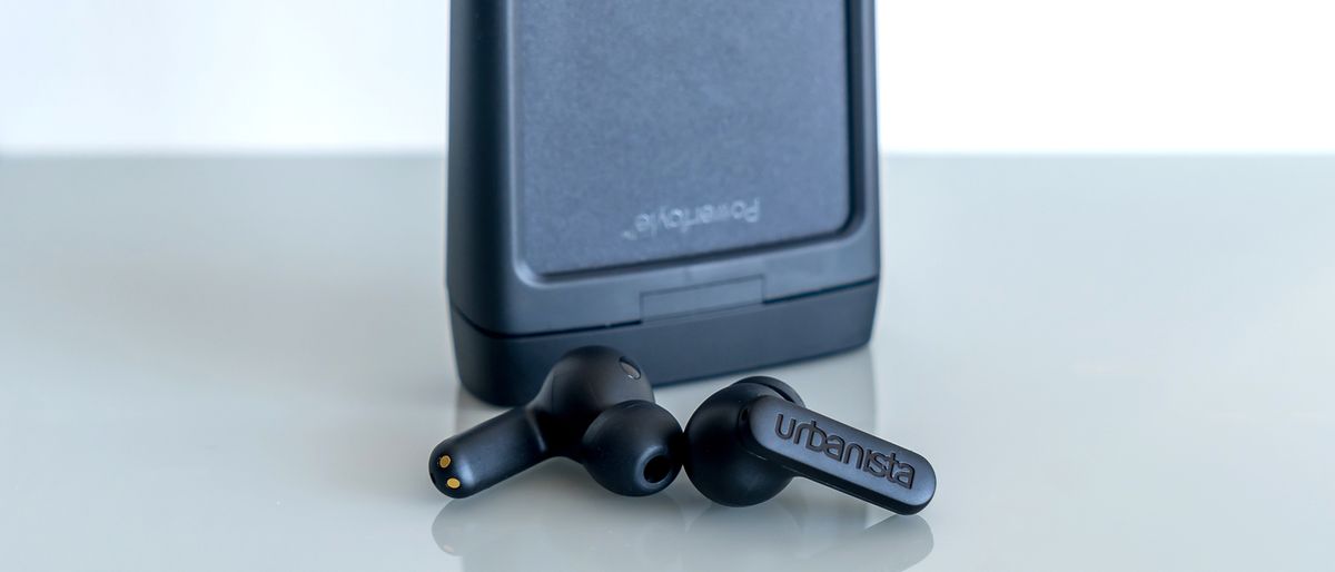 Urbanista Phoenix earbuds in front of case.