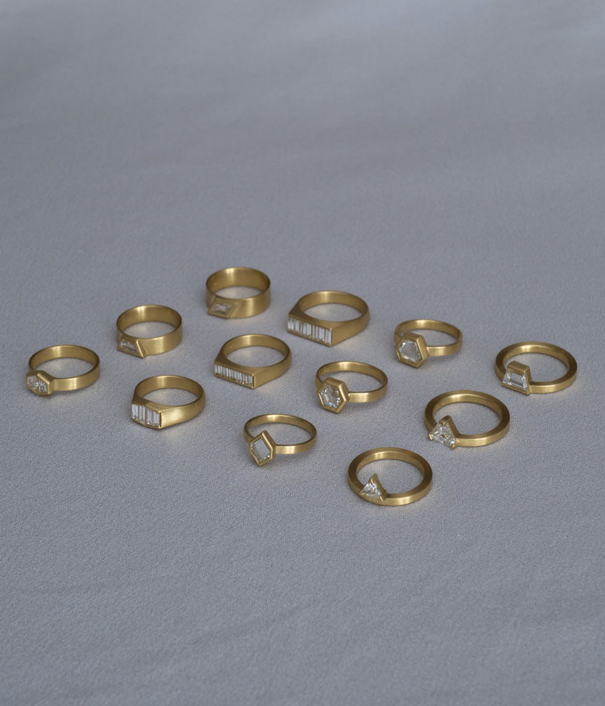 Selection of gold diamond rings against a grey backdrop